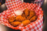 A basket of crispy golden wings with dipping sauce on the side, set against an urban diner table.