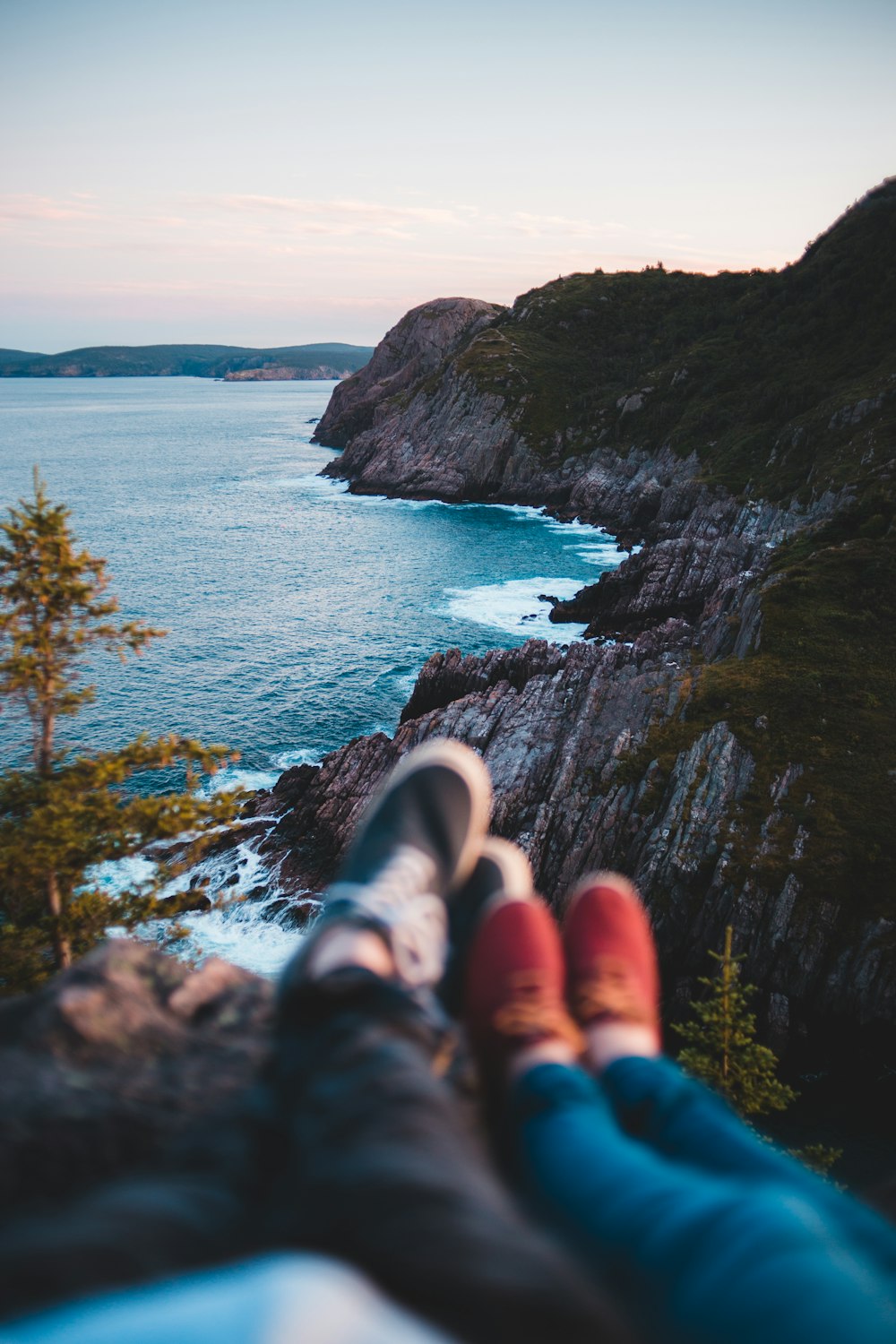 person in blue denim jeans sitting on cliff over the sea during daytime