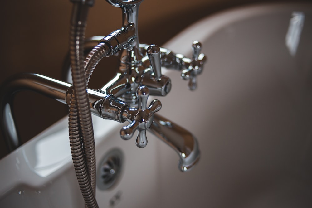 silver water faucet on white ceramic sink