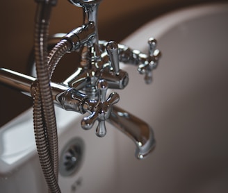 silver water faucet on white ceramic sink