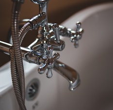 silver water faucet on white ceramic sink