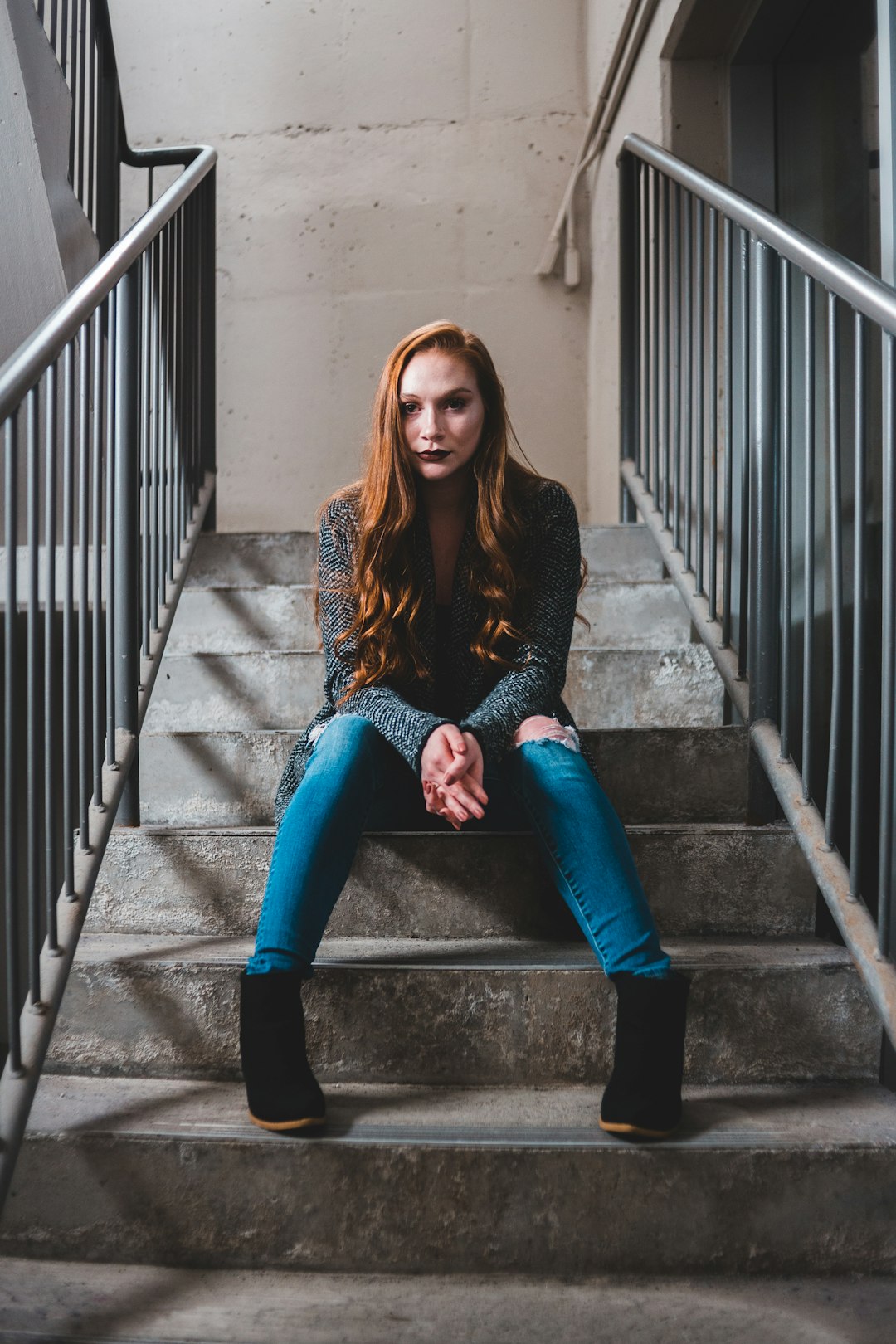 woman in black sweater and blue denim jeans sitting on stairs