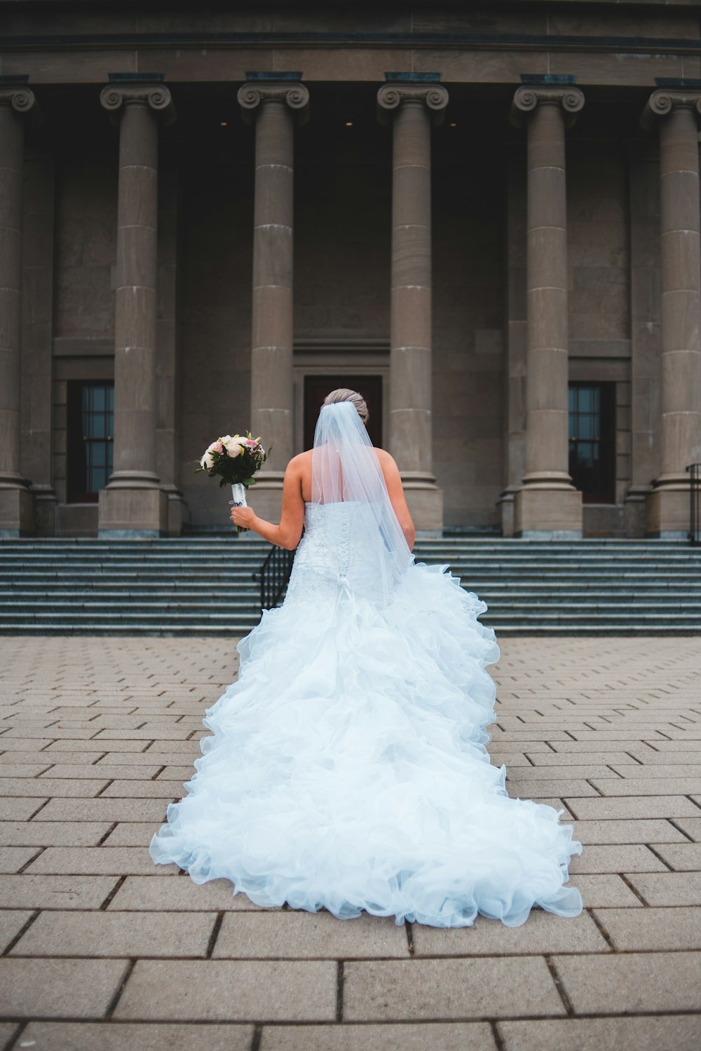woman in white wedding dress standing on brown brick floor during daytime