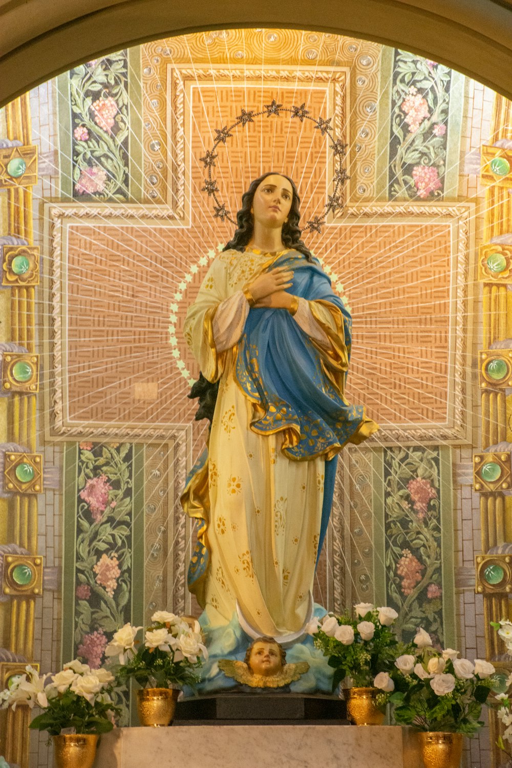 Statua della Vergine Maria su tessuto floreale marrone e bianco