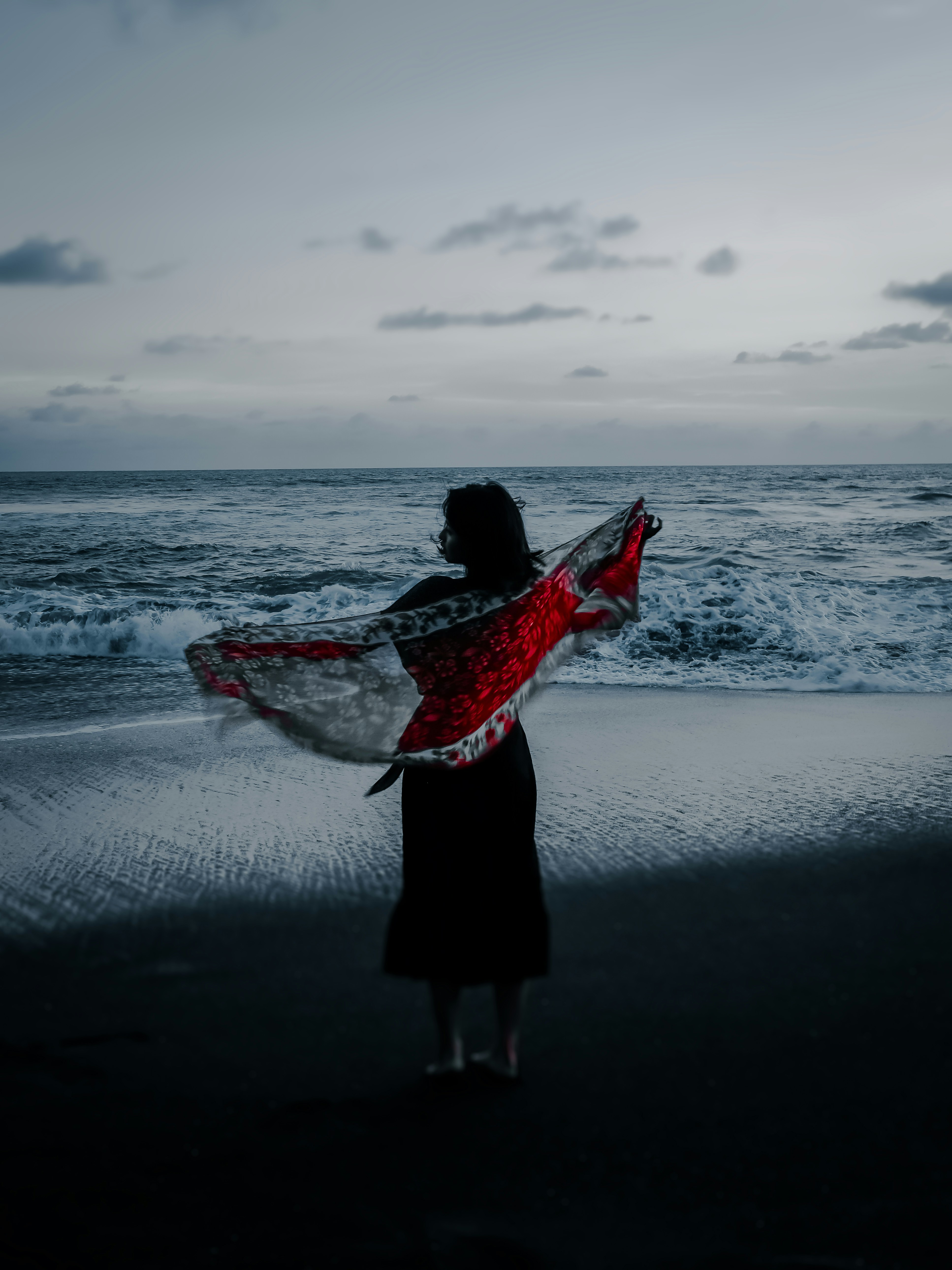 woman in black dress holding white and red surfboard on beach during daytime