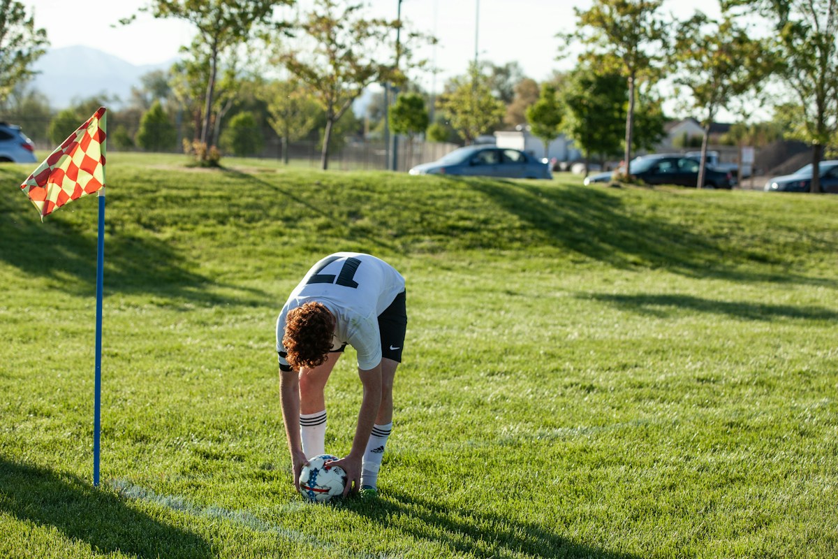 A soccer player in a blue and white jersey kicks a ball on a grassy field, perfect for youth sports celebration themes.