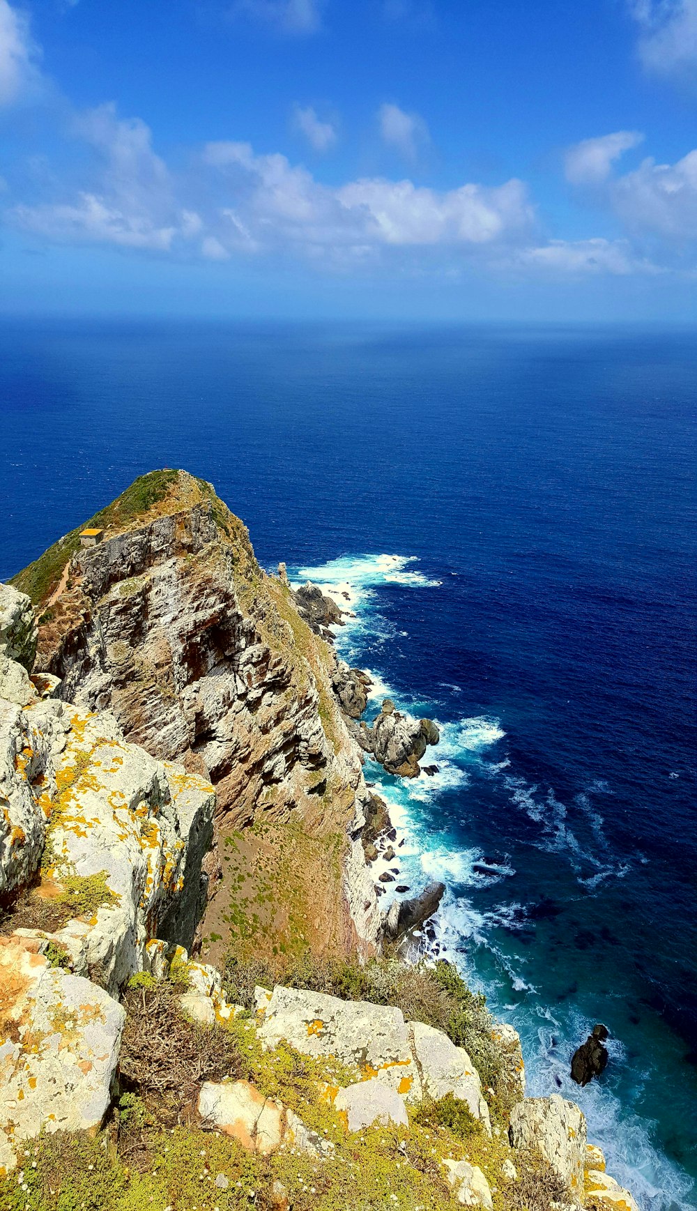 brown and green rock formation beside blue sea during daytime