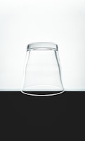 An inverted clear glass placed on a flat surface, contrasting against a minimalistic black and white background.