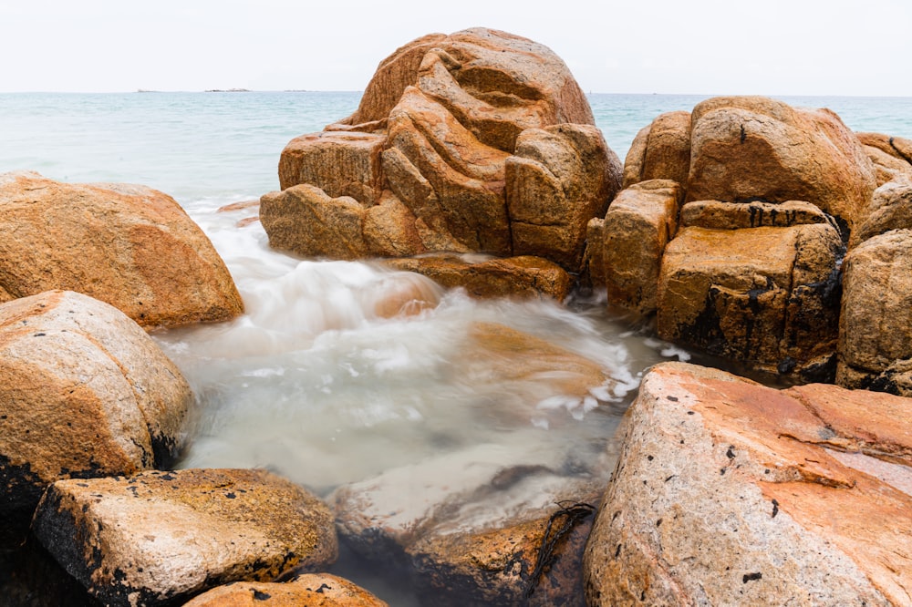 Formación rocosa marrón cerca del cuerpo de agua durante el día