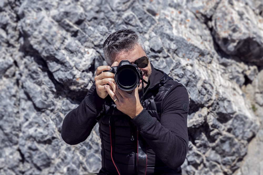 man in black leather jacket taking photo using black dslr camera