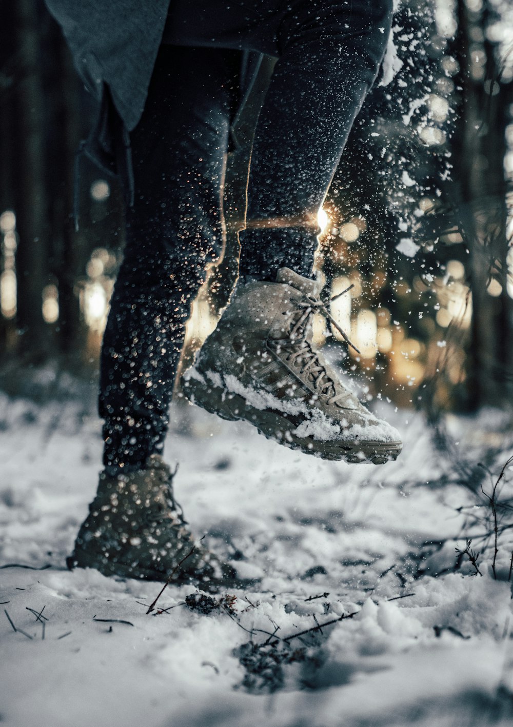 person in black pants and black boots walking on snow covered ground during daytime