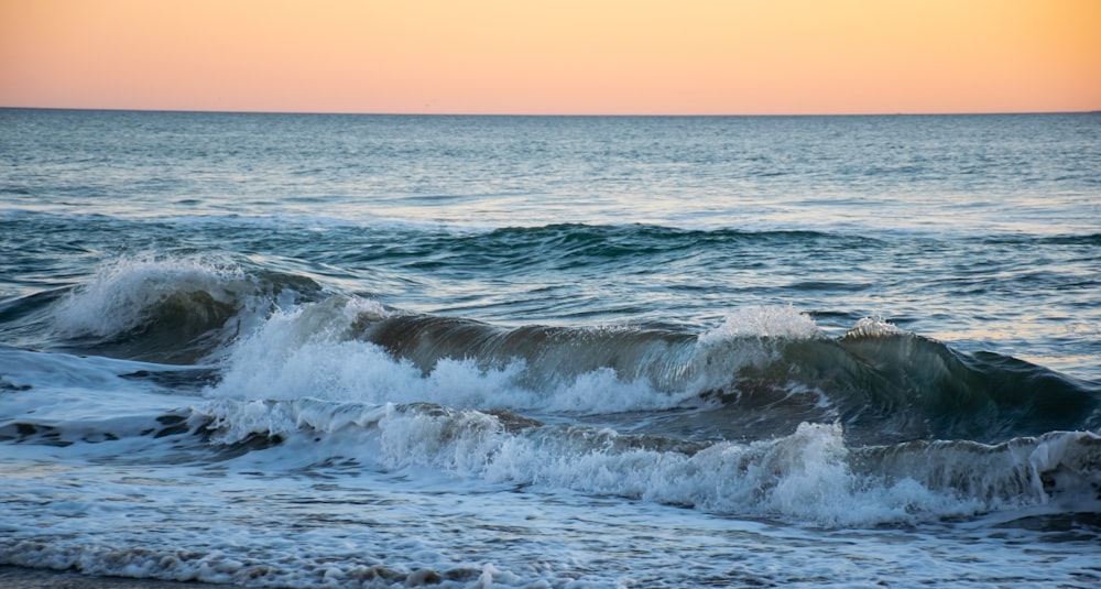 ocean waves crashing on shore during sunset