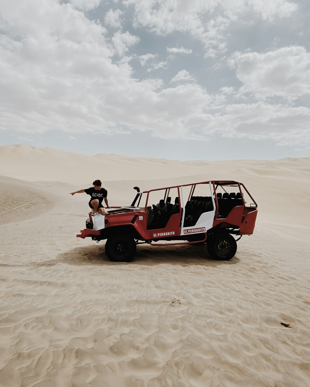 2 people riding red and black golf cart on brown sand during daytime