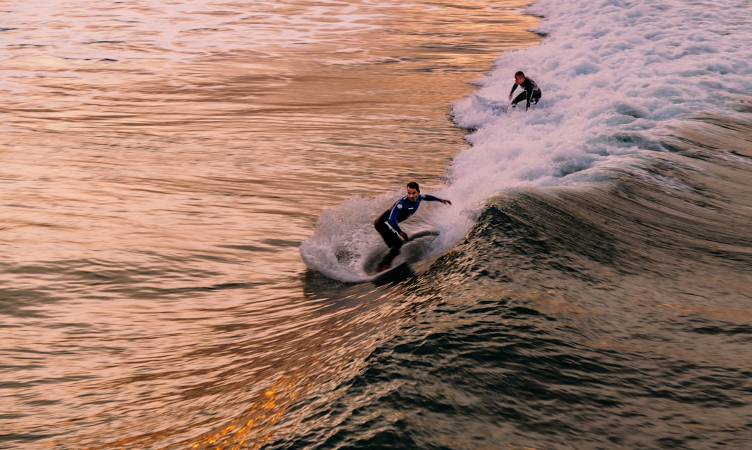 2 men surfing on sea waves during daytime