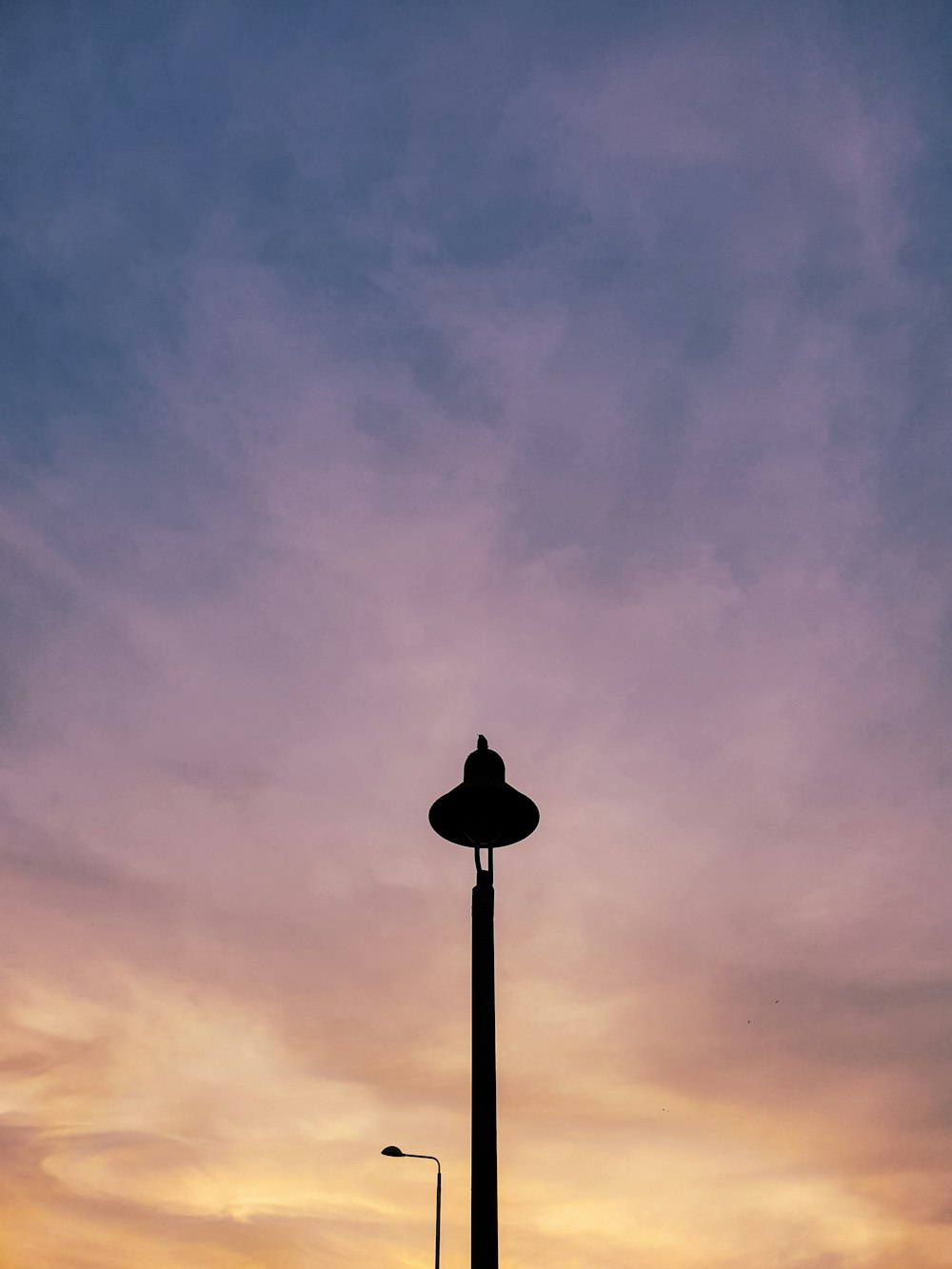 black street lamp under gray clouds