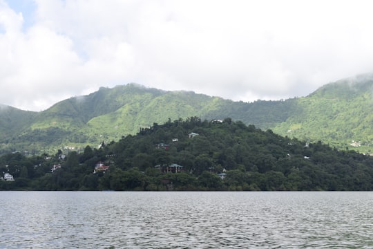 green mountain beside body of water during daytime in Uttarakhand India