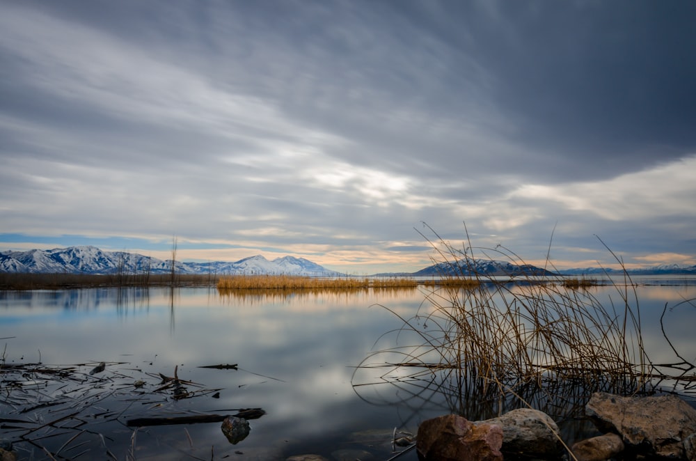 lake near mountain under cloudy sky during daytime