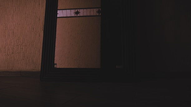 Close-up of a beveled mirror edge reflecting a modern, elegant interior with warm lighting.