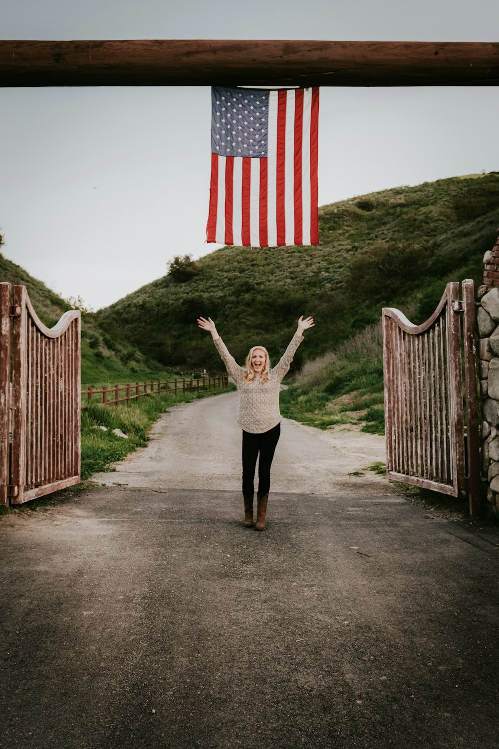 Frau in weiß-schwarzem Kleid steht auf dem Weg mit der US-Flagge auf dem Rücken