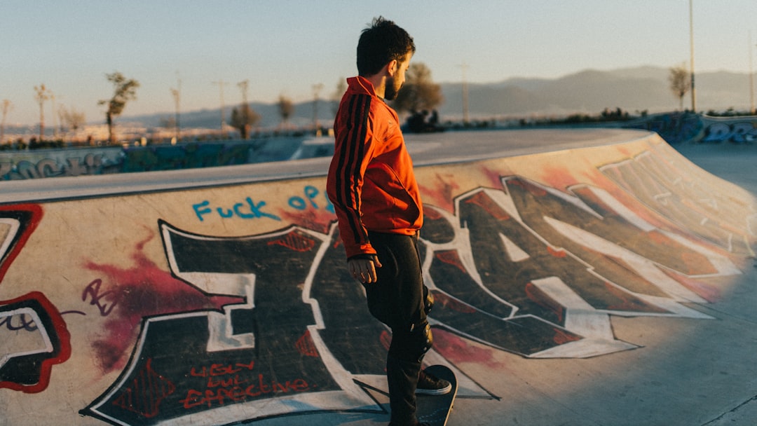 man in orange and black jacket standing on basketball court during daytime,