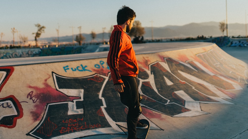 man in orange and black jacket standing on basketball court during daytime