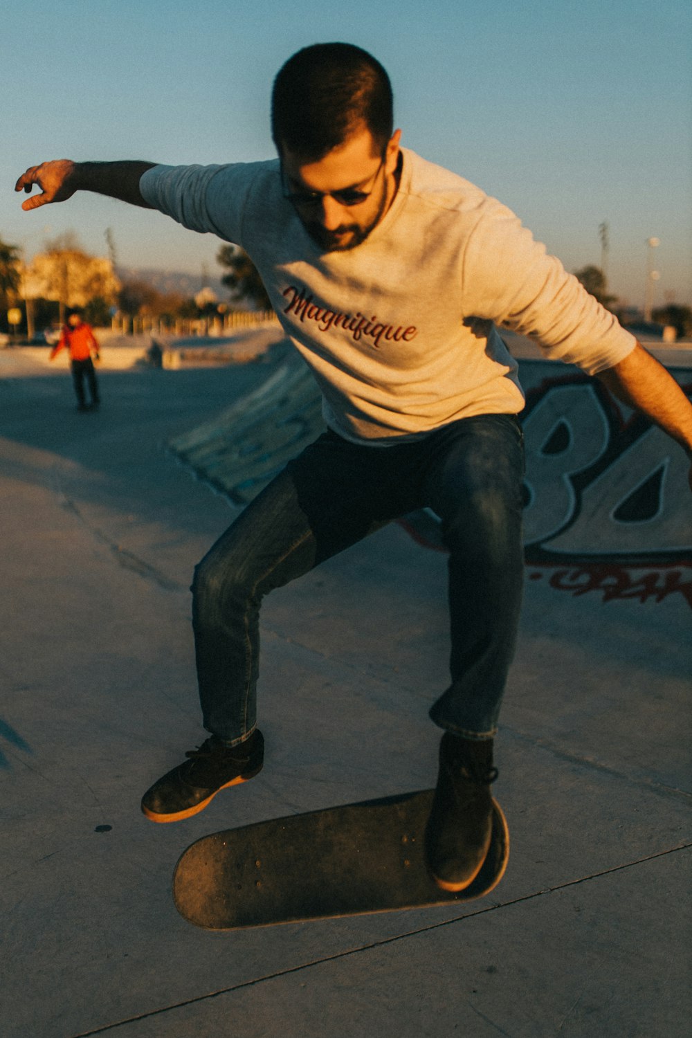 man in white and black hoodie and black denim jeans sitting on black and white skateboard