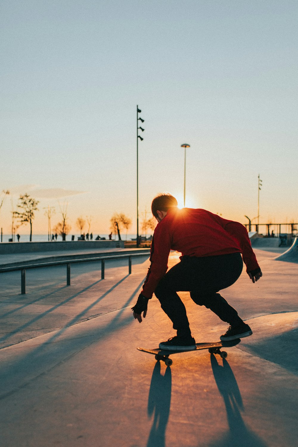 uomo in camicia rossa che cavalca lo skateboard durante il giorno