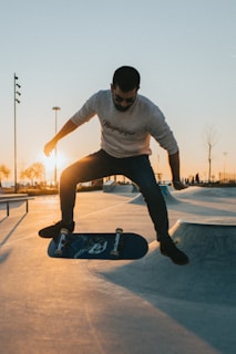 Golden hour light casting long shadows on a skateboard ramp with a girl mid-trick.