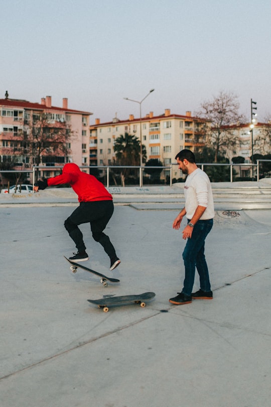 man in red hoodie and woman in white t-shirt riding on black skateboard during daytime in Bostanlı Turkey