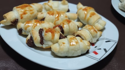 Golden croissants and chocolate-filled pastries arranged invitingly on a rustic wooden table.