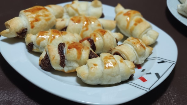 Freshly baked croissants arranged on a rustic ceramic plate.