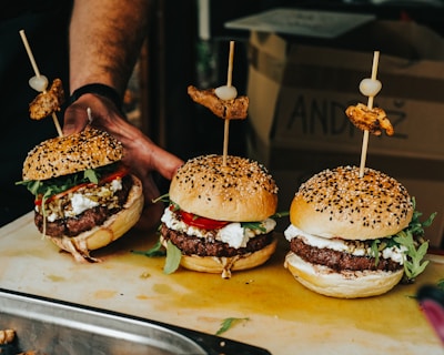Artisanal burgers freshly prepared and served with rustic side dishes on a wooden board.