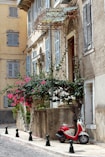 red motorcycle parked beside white concrete building during daytime