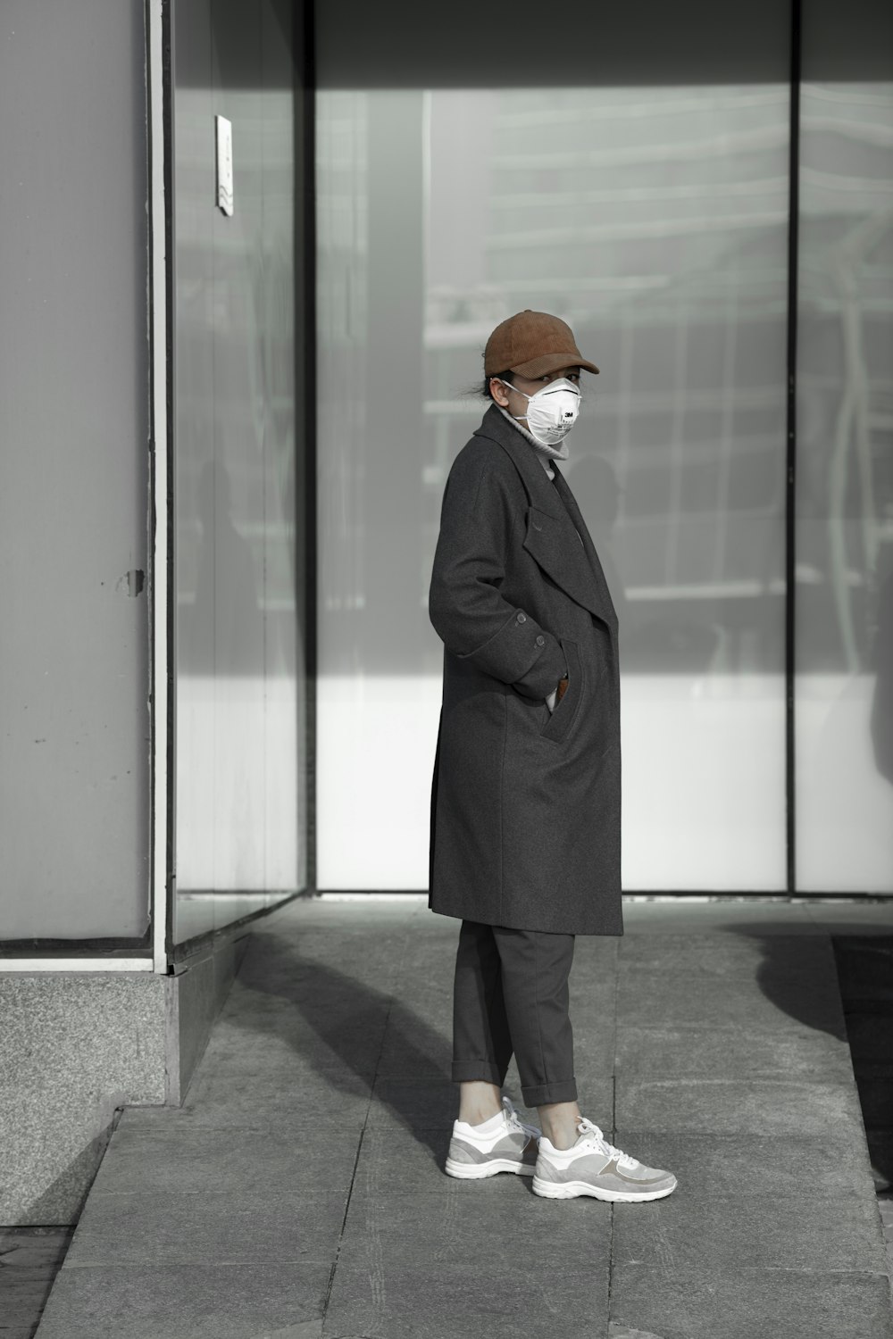 Frau im schwarzen Mantel vor Glastür