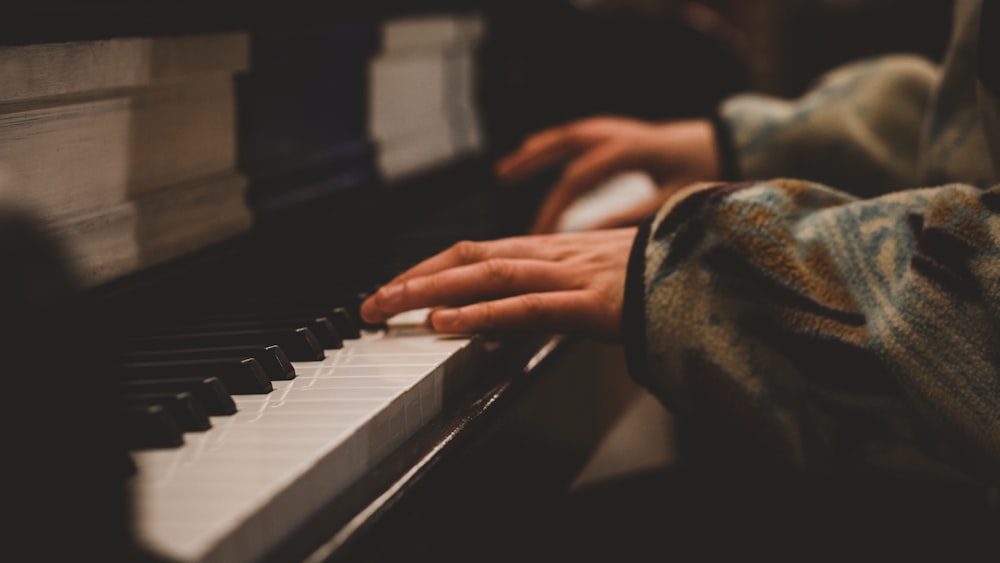 person playing piano in grayscale photography