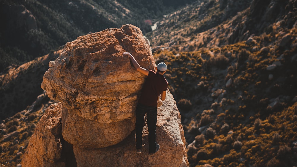 man in black jacket and black pants standing on brown rock formation during daytime