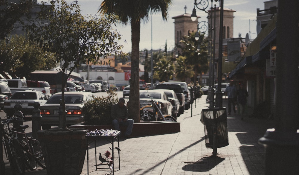 man in black jacket sitting on brown wooden bench during daytime