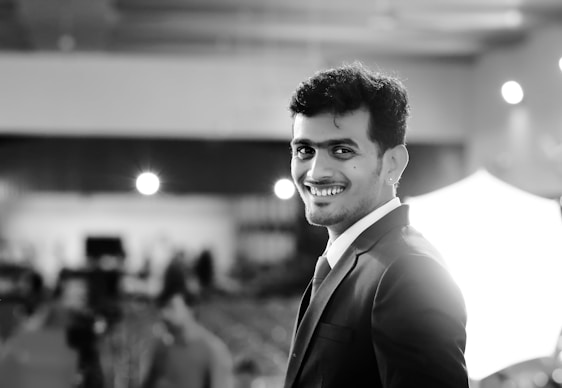 A stylish young man in a suit smiling confidently in an elegant setting.