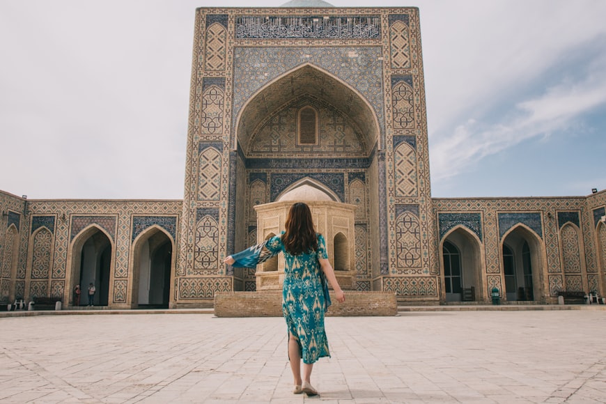 Una donna di spalle ammira dei monumenti beige e azzurri in Unzbekistan