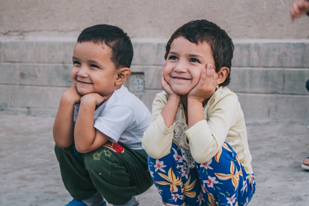 two young boys sitting on the ground smiling