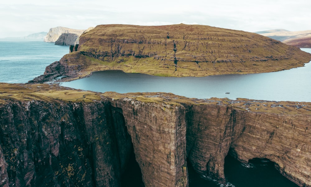 brown rock formation on body of water during daytime