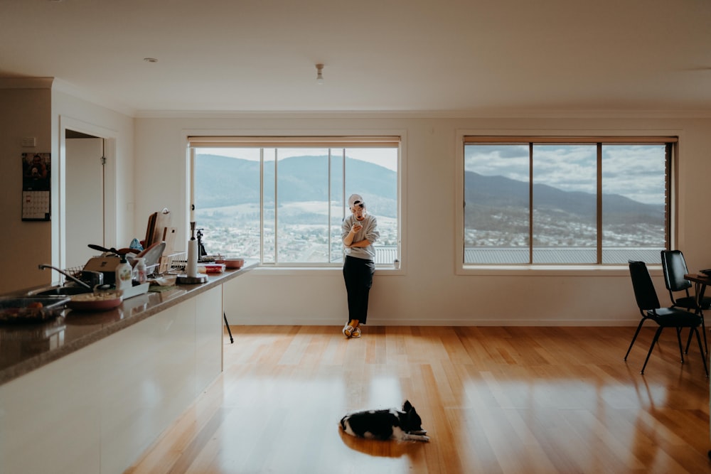 woman in white t-shirt and black pants standing near window