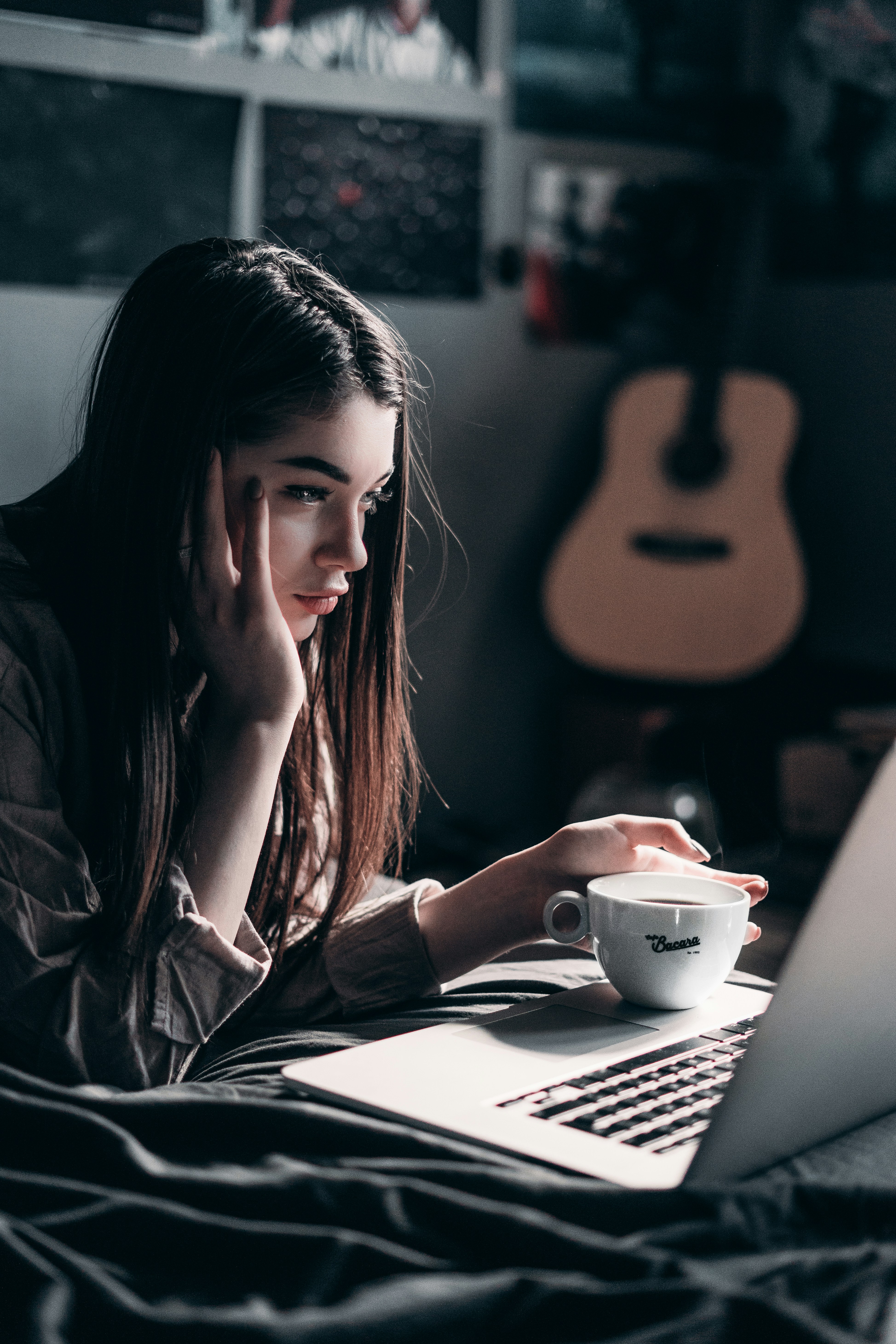 woman in black leather jacket holding white ceramic mug in frond of a laptop
