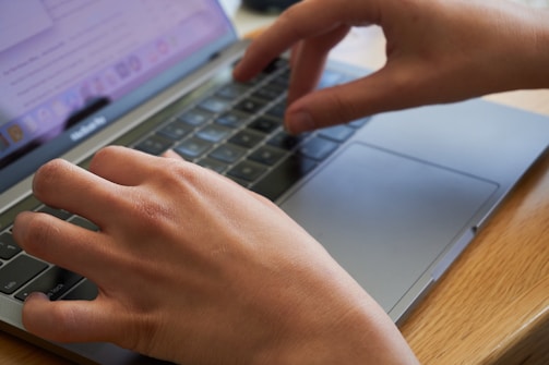 Close-up of hands typing code on a laptop with a warm background.