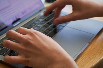 Hands typing on a refurbished laptop with a cozy home office background.