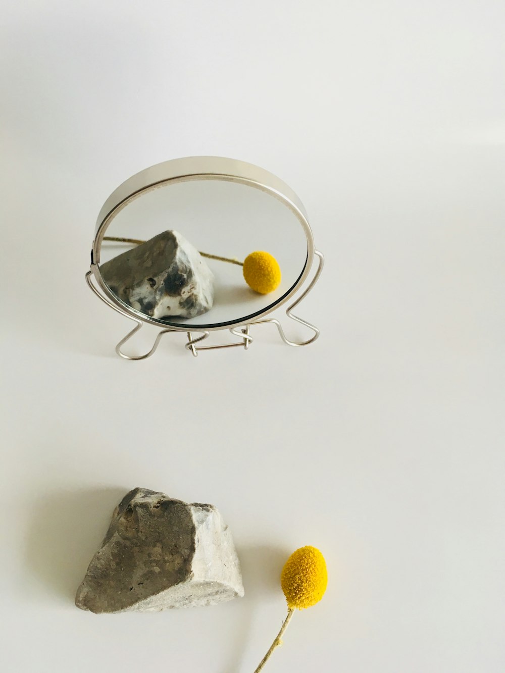 a mirror with a rock and a yellow ball on it