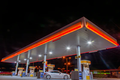 Fuel nozzle dispensing gasoline into a car tank at a bright, modern station.