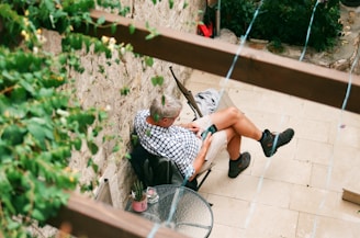 man in white tank top and black and white shorts sitting on gray metal chair