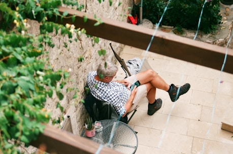 man in white tank top and black and white shorts sitting on gray metal chair
