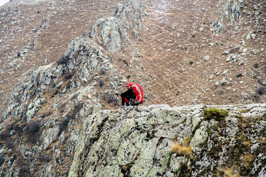 person in red jacket climbing on rocky mountain during daytime in Kaleybar Iran